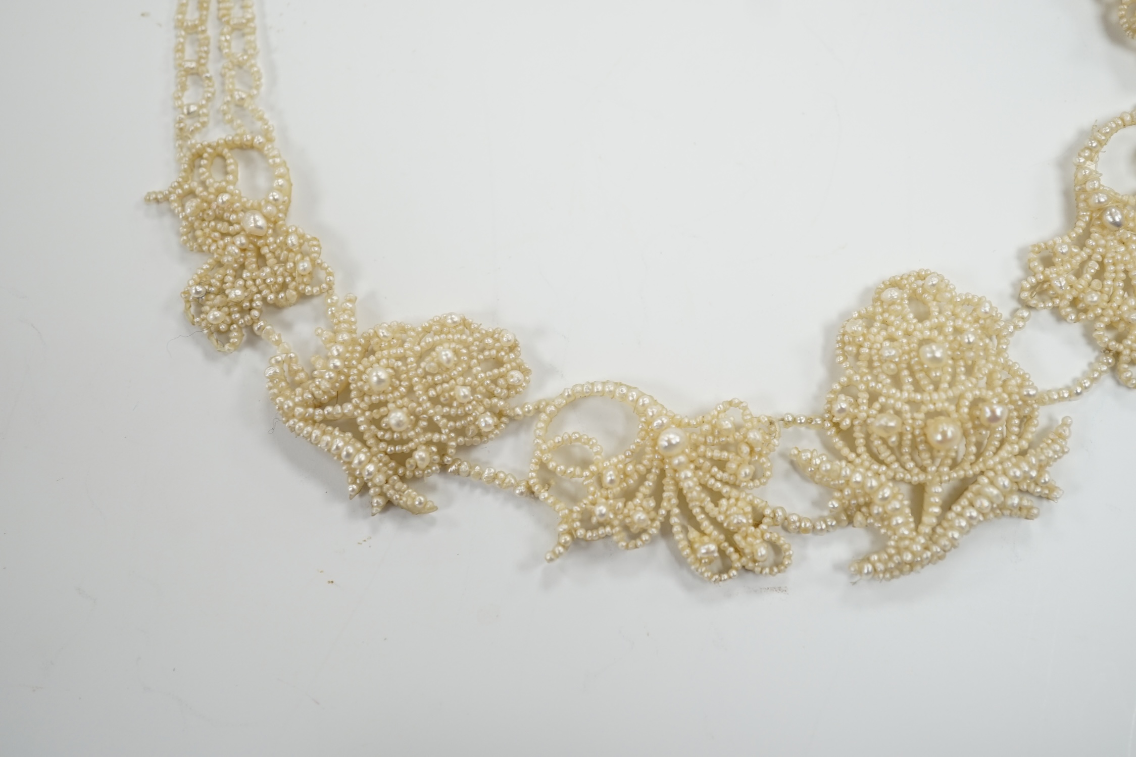 A cased Regency twin strand seed pearl choker necklace with scrolling floral motifs and yellow metal clasp, 34cm.